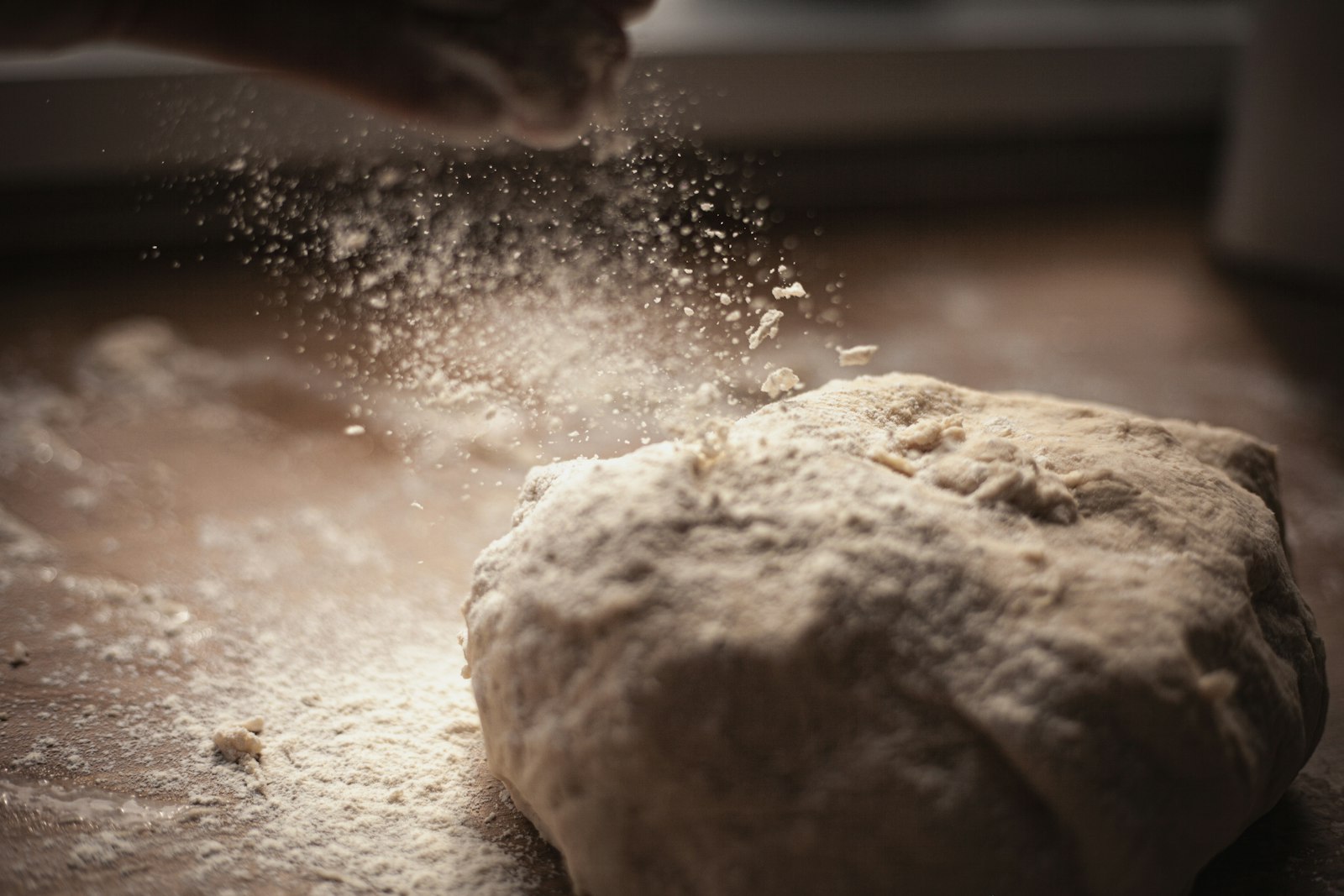 Flour falling onto a mound of dough